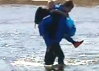 На видео засняли, как школьник из Иркутска носит на себе детей через реку на занятия